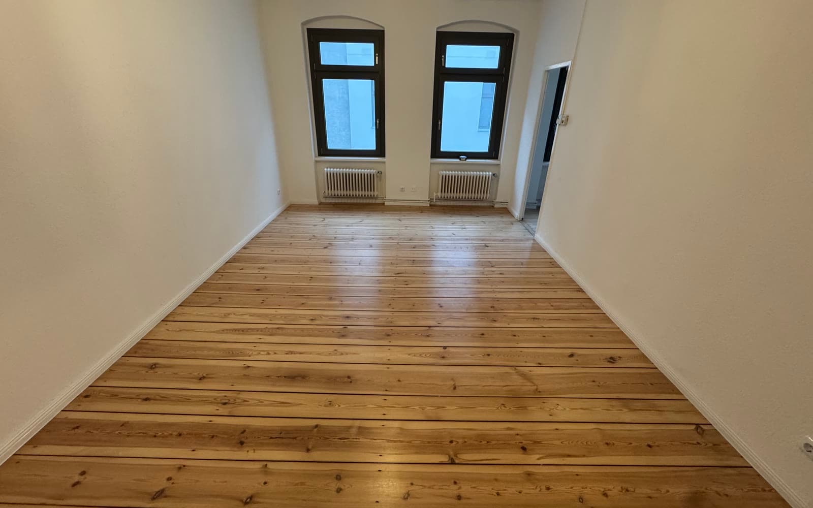 Leere Altbauwohnung mit abgezogenem Dielenboden und zwei Fenstern